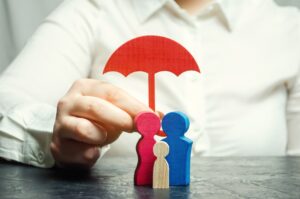 Insurance agent services. Concept of life and health insurance. Social protection of people. Security and support. Miniature wooden figures of people in the form of a family